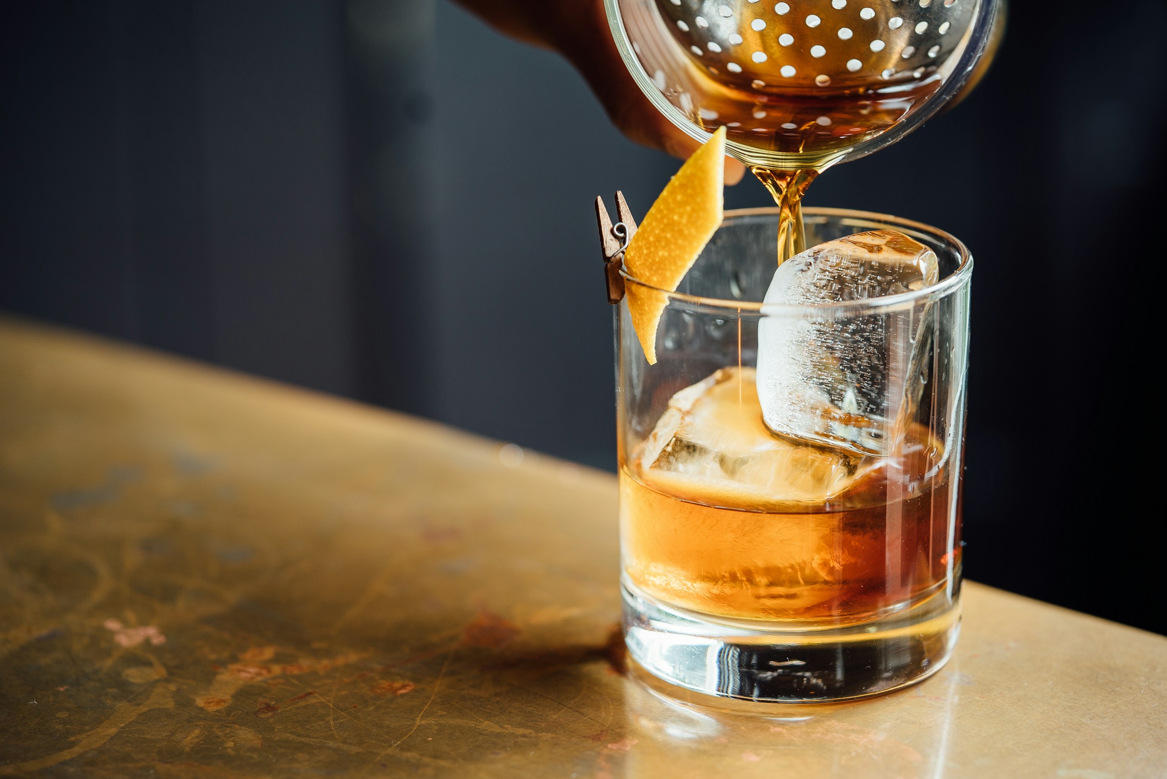 A cocktail being finished at the bar, warm low light